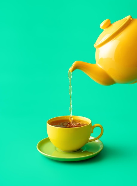 Pouring tea in a cup minimalist on a green background