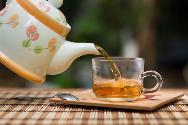 Pouring tea with teapot on wooden table