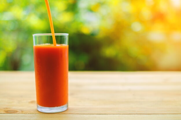 Pouring tomato juice into a glass on wooden table