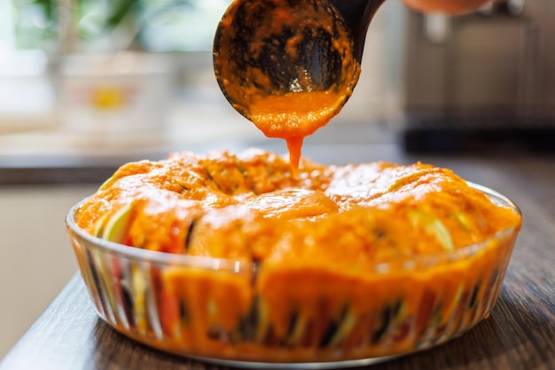 Pouring tomato sauce over vegetable tian