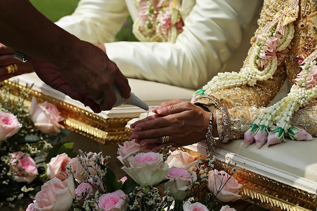 Photo pouring water from the conch shell into the bride's hands at a thai wedding