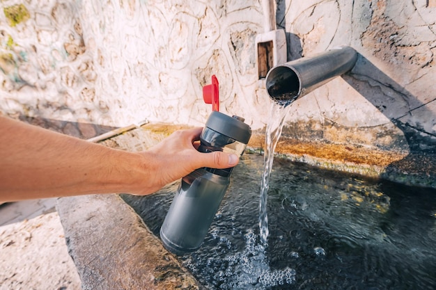 Pouring water from a spring source at camping or hiking Clean looking water can be contaminated and dangerous to health