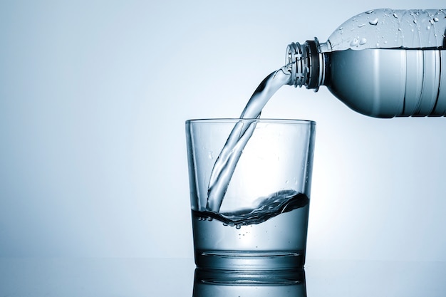 Pouring water into a tumbler in close up