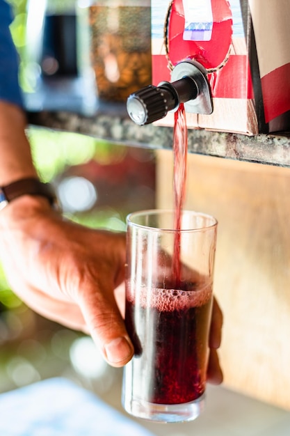 Pouring wine in glass from 3l wine box close up