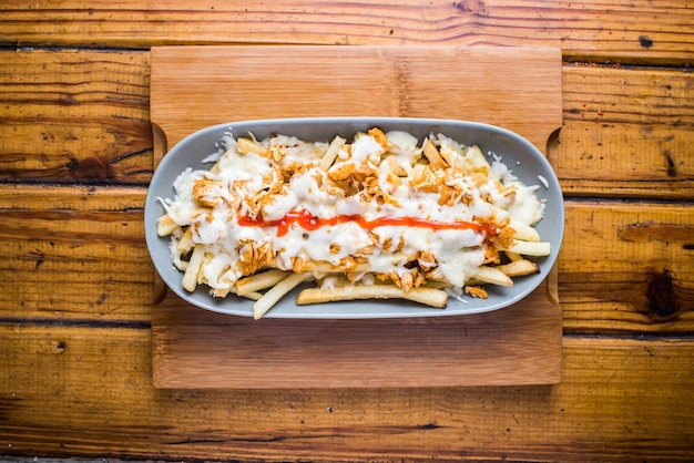 Poutin fries loaded with mayo dip isolated on wooden board top view on table fastfood