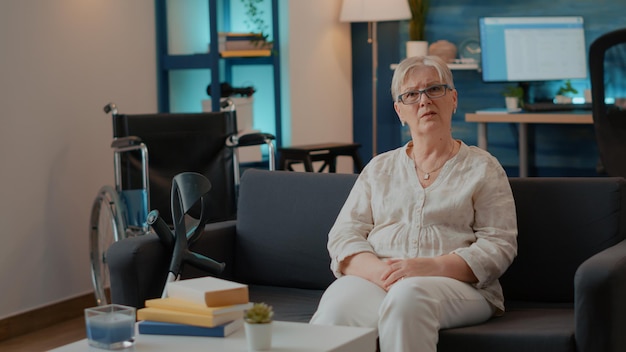 POV of elder woman talking on online videoconference in living room. Retired adult with crutches starting remote conversation on teleconference meeting call, discussing with people.