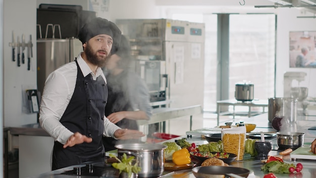 グルメシェフのPOVがカメラで料理番組のビデオを録画し、プロのキッチンで本格的な料理のレシピを作成します。オンライン美食のクラスのために料理のvlogを撮影している若い男。ハンドヘルドショット。