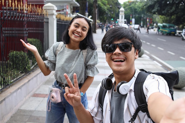 POV of happy young Asian couple taking a selfie smiling at the camera during travelling the city