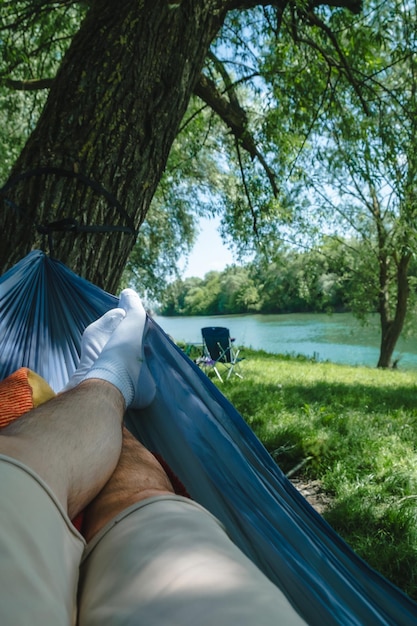 pov man laying down on hammock resting at riverside summertime