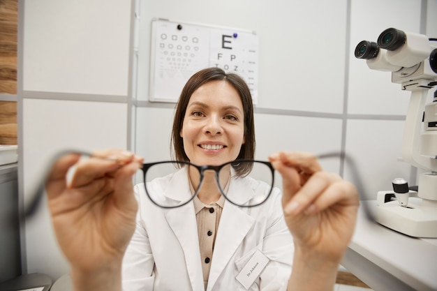 Foto pov shot van glimlachende vrouwelijke optometrist bril te zetten