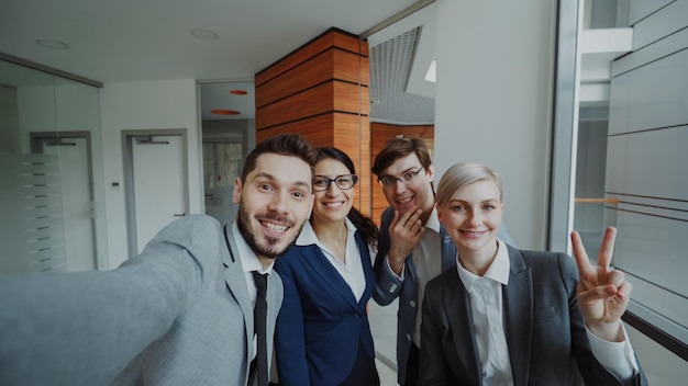 Pov van happy business team dat selfie portret maakt op smartphone camera en poseert voor groepsfoto