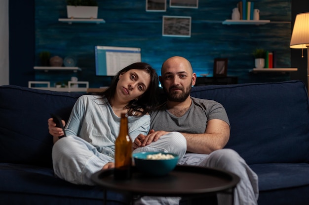 POV of young partners watching movie on TV screen, doing leisure activity and relaxing on couch. Man and woman looking at film on television channel to have fun, entertainment and excitement.