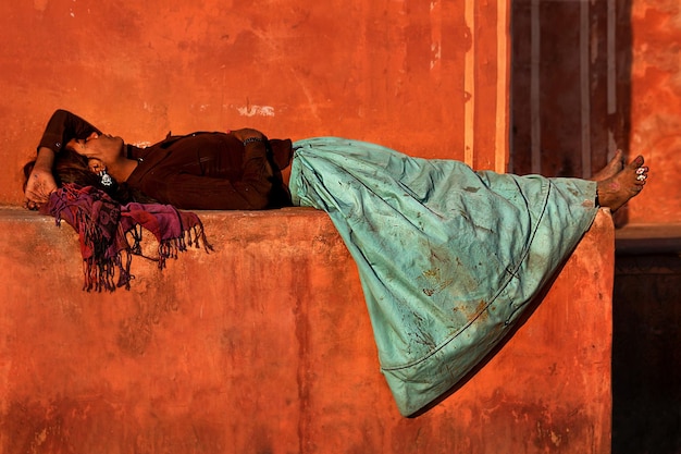 아시아의 빈곤. 피곤하고 가난하고 아름다운 소녀가 델리의 거리에서 쉬고 있습니다. 인도