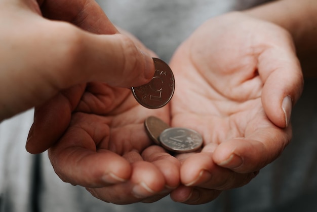 Poverty financial social problems poor charity help concept Hand giving money in palms closeup Selective focus on coin