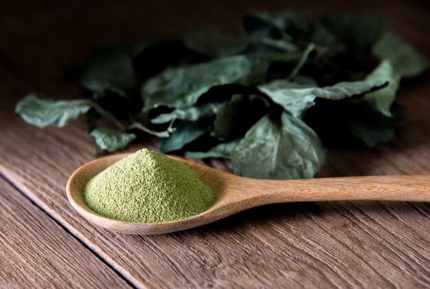 Powder green tea and green tea leaves on wooden.