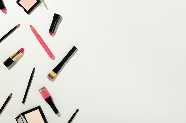 powder, highlighter, lipstick, makeup brushes and nail polish isolated on white