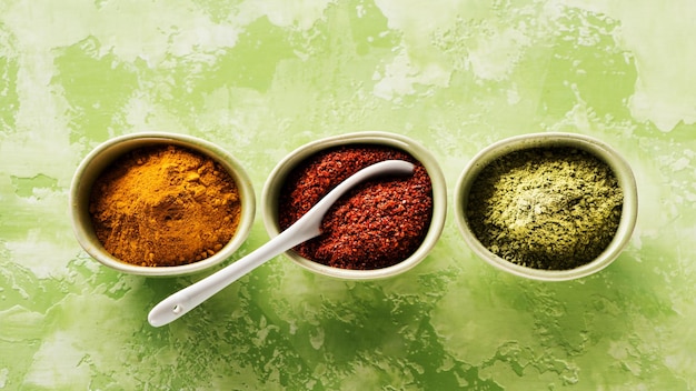 Photo powder spices spicy seasoning.  turmeric, coriander and hot chili in bowls on concrete background, top view