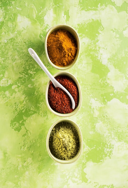 Powder spices spicy turmeric, coriander and hot chili  in bowls on a concrete background, top view