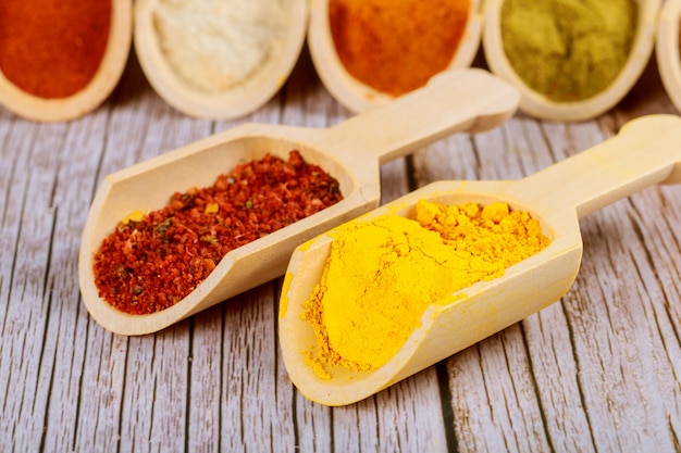 Powdered asian spices on wooden scoops on white table