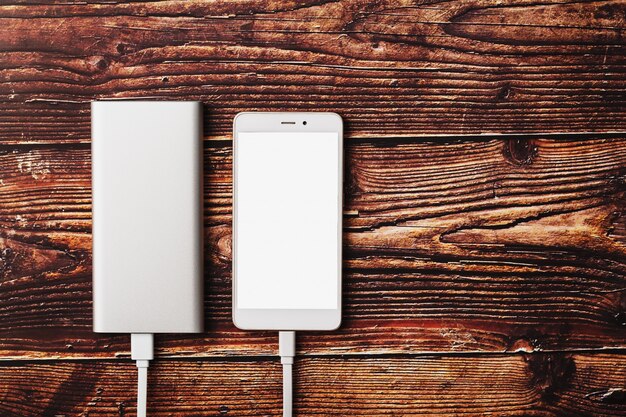 Power Bank charges a smartphone on a wooden background.