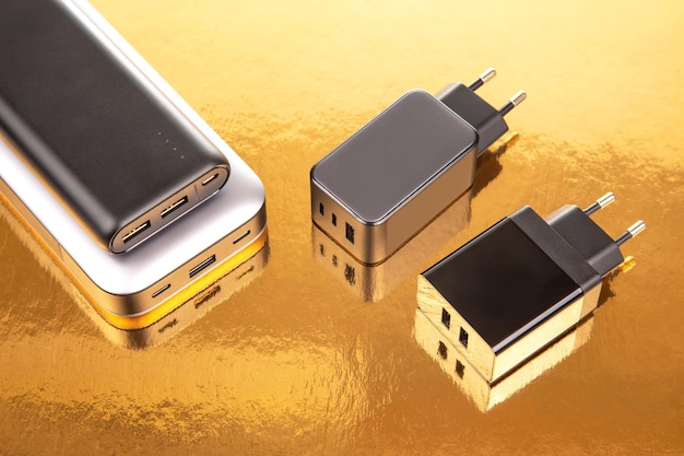 Блок питания и зарядная вилка на золотом фоне Электронные устройства для зарядки гаджетов