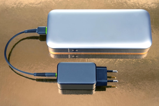 Power bank and charging plug with cable on a golden background Electronic devices for charging gadgets