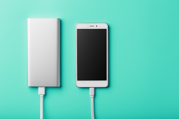 Power Bank laadt je smartphone op op een blauwe achtergrond. Universele externe batterij voor gadgets vrije ruimte en minimalistische compositie.