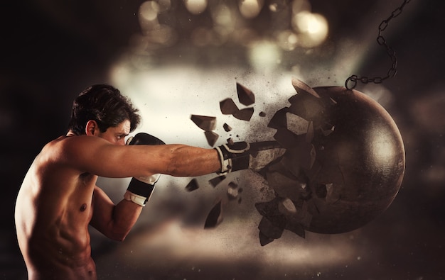 Photo power and determination of a young muscular boxer against a wrecking ball