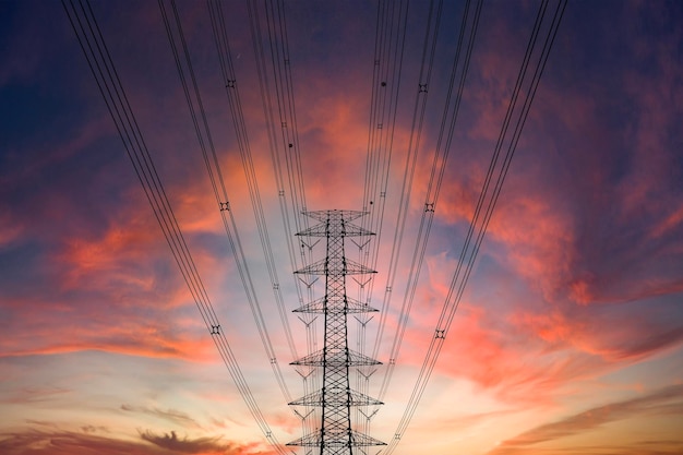 A power line crosses the foreground of a dramatic sunset The setting sun casts a warm glow over the landscape silhouetting