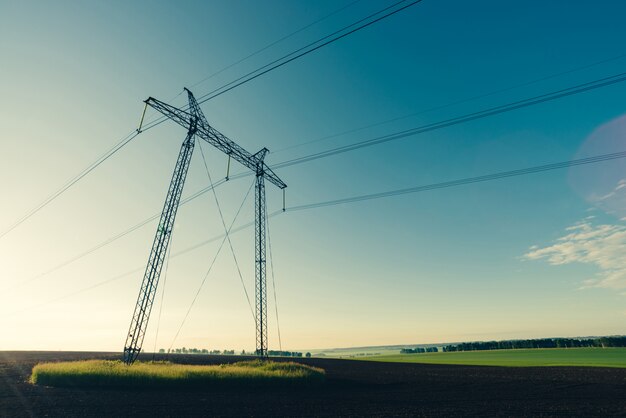 Power lines on  blue clear sky in backlight from sunlight close-up. 