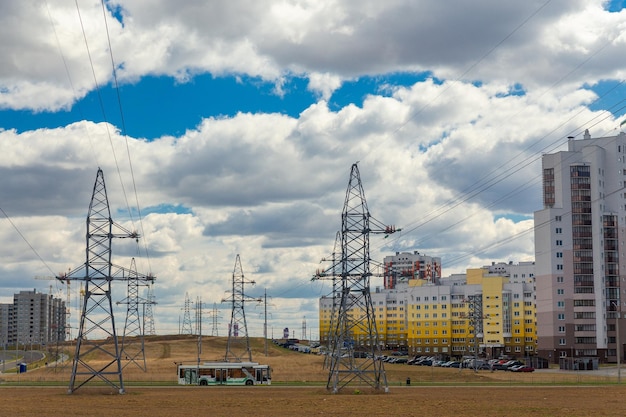 Линии электропередач в городе возле жилых домов на фоне голубого неба