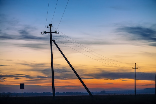 Power lines in field on sunrise