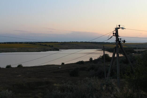 A power lines on a pole next to a body of water