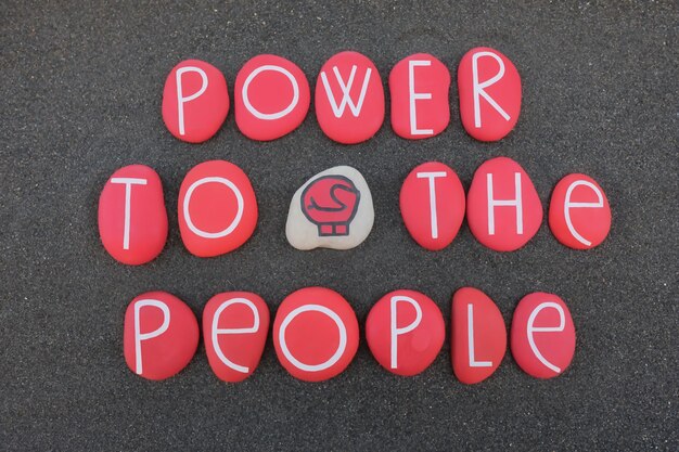 Power to the people protest slogan composed with red colored stones over black volcanic sand