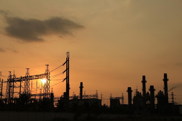 写真 クリーン エネルギーのコンセプトを備えたオレンジ色の光の夕日に対する発電所