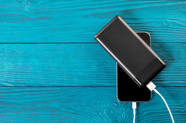 Powerbank charges smartphone isolated on wood background