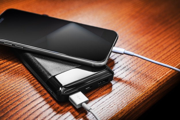 powerbank charges smartphone isolated on wood