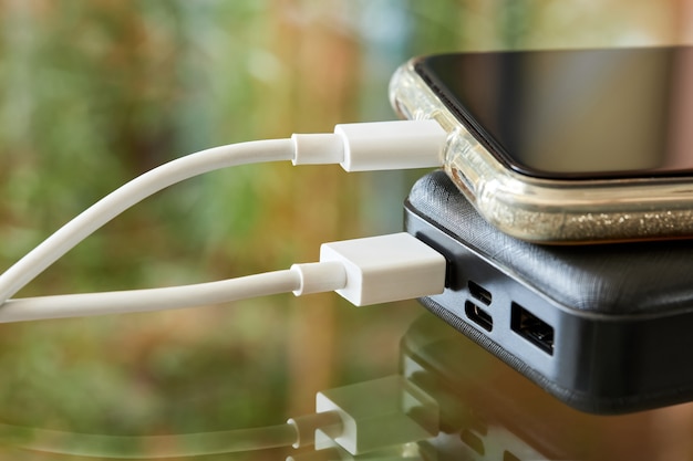 powerbank charges smartphone using a usb cable on a glass surface