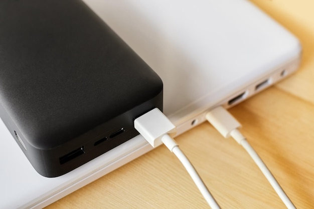 Powerbank laadt een laptop op via USB type C-kabel op een houten ondergrond