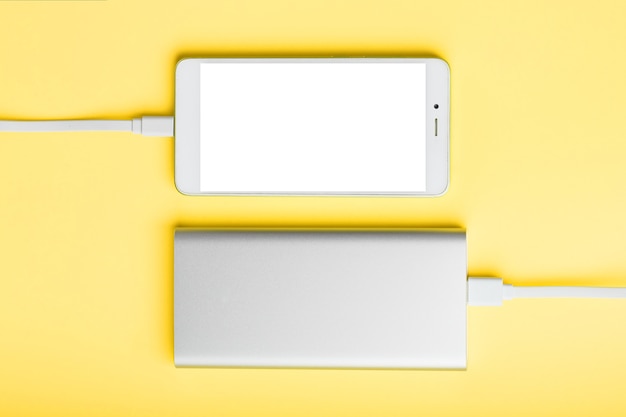 Foto powerbank laadt je smartphone op op een gele ondergrond