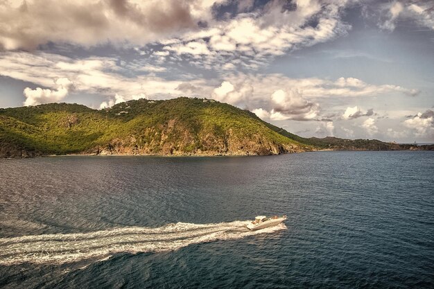 Photo powerboat travel in blue sea on cloudy sky in gustavia stbarts travel on boat wanderlust summer vacation on tropical island water transport and vessel beautiful landscape with mountains