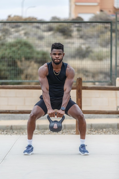 Powerful black athlete doing exercises with kettlebell