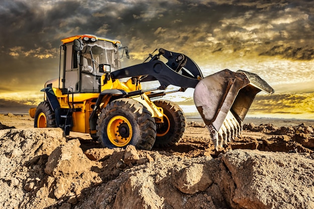 Powerful bulldozer or loader moves the earth at the construction site against the sky An earthmoving machine is leveling the site Construction heavy equipment for earthworks