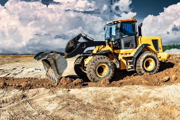 Powerful bulldozer or loader moves the earth at the construction site against the sky An earthmoving machine is leveling the site Construction heavy equipment for earthworks