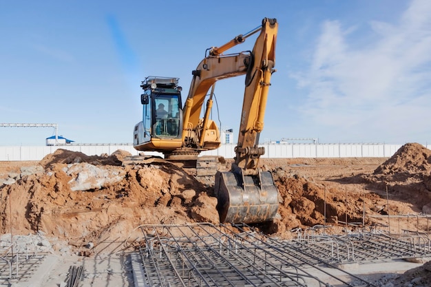 A powerful caterpillar excavator digs the ground against the blue sky Earthworks with heavy equipment at the construction site