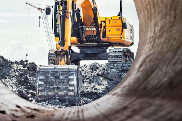 A Powerful Caterpillar Excavator Digs The Ground Against The Blue Sky Earthworks With Heavy Equipment At The Construction Site