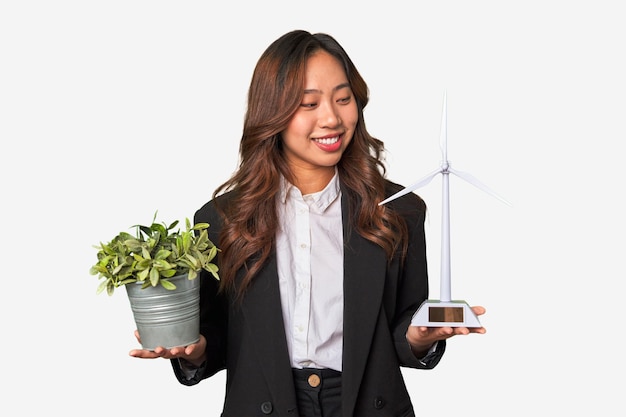 元気な植物と風車の模型を手にするパワフルな中国人女性実業家