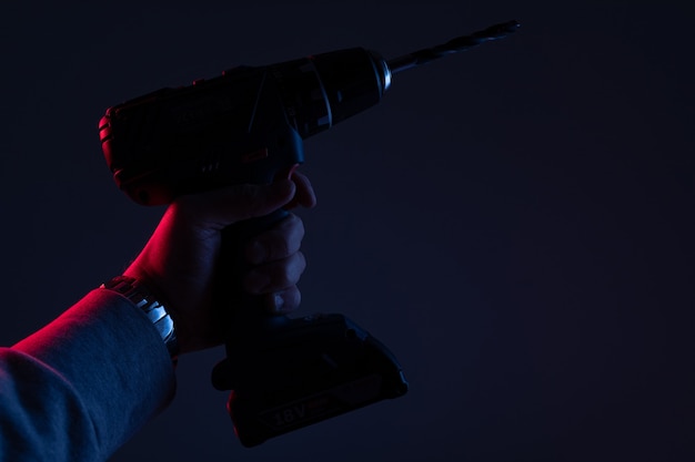 Photo powerful drill for repair close-up in neon light on a black wall