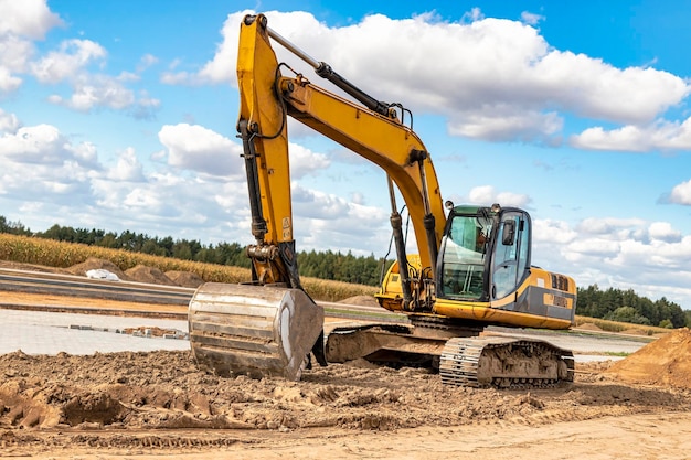 Powerful excavator at a construction site against a blue cloudy sky Earthmoving equipment for construction Development and movement of soil