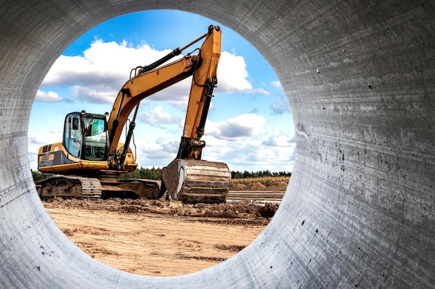 Powerful excavator at the construction site View of the excavator through the pipe Closeup of earthmoving machinery Construction equipment for earthworks Soil development